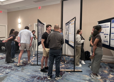 PCB Poster Session where scientists animatedly discuss their work with colleagues in front of their posters