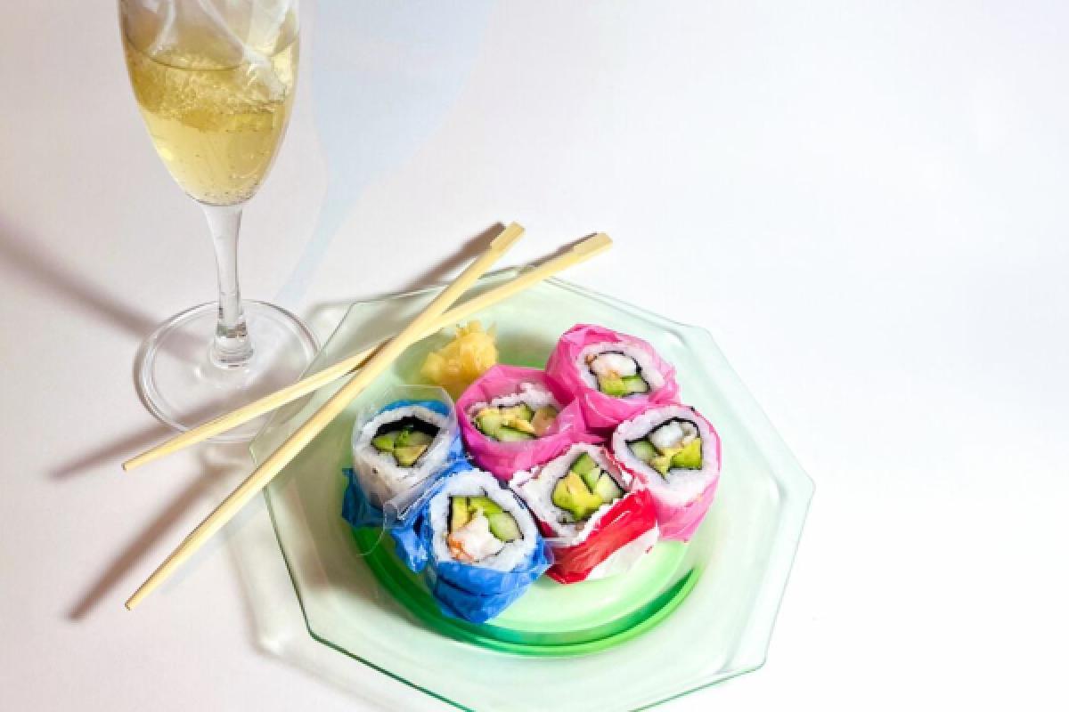Stock photo of colorful sushi, chopsticks, and a glass of wine