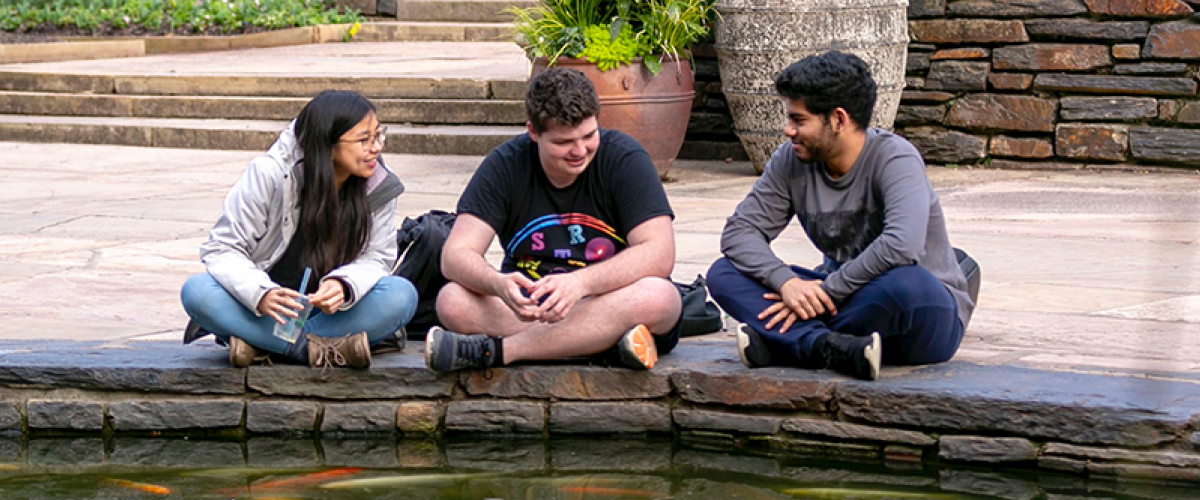 3 Students sitting at the coi pond in the Duke gardens
