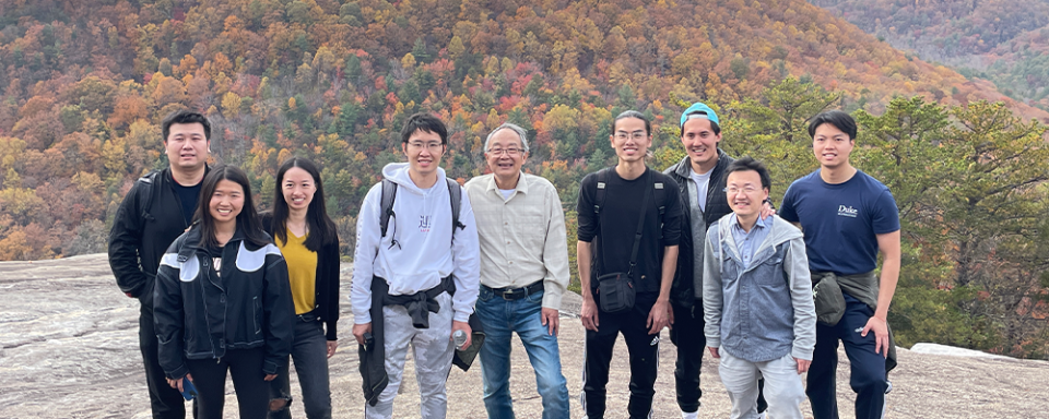 Xiao-Fan Wang and his lab team on a mountain top surrounded by colorful autumn foliage. 