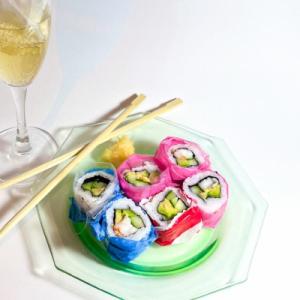 Stock photo of colorful sushi, chopsticks, and a glass of wine